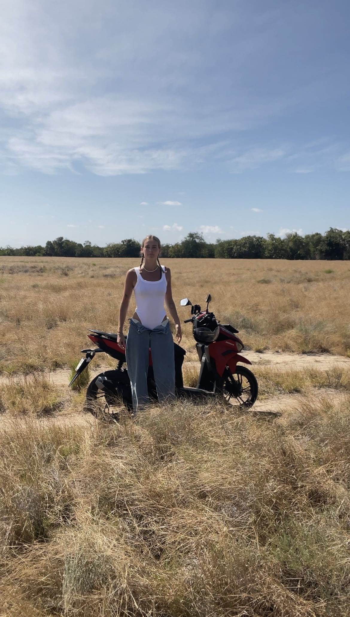 Riding a scooter through dry grass fields on Sumba's east coast